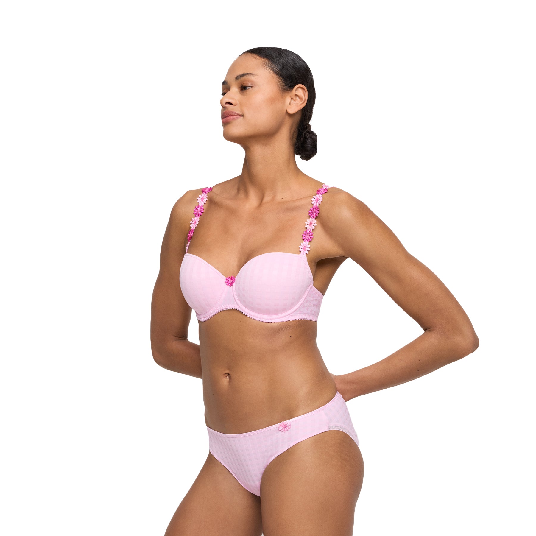 Woman wearing a matching light pink textured bra with floral appliqué straps and coordinating thong with floral appliqué detail.