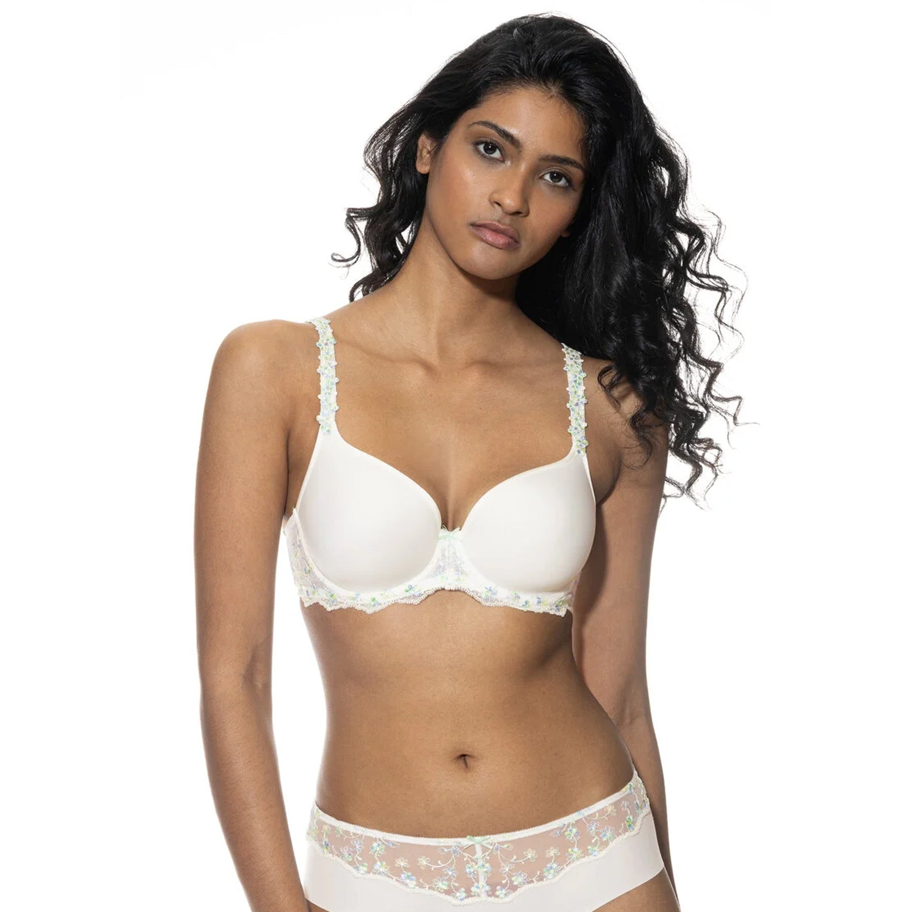 Woman wearing a white bra with floral embroidery and matching brief, facing forward with a relaxed expression.