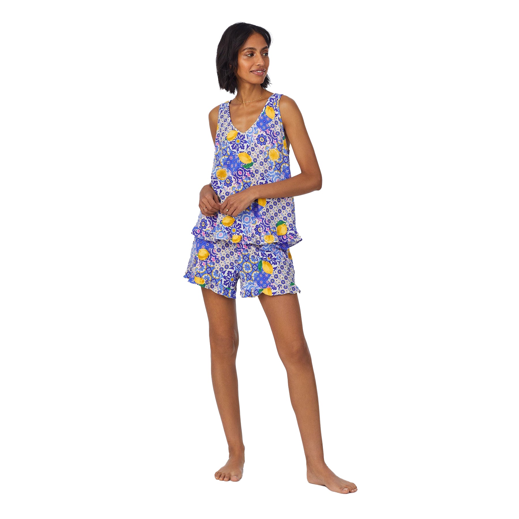 Woman wearing a sleeveless blue printed pajama set with lemons and floral tiles, shown from the front.