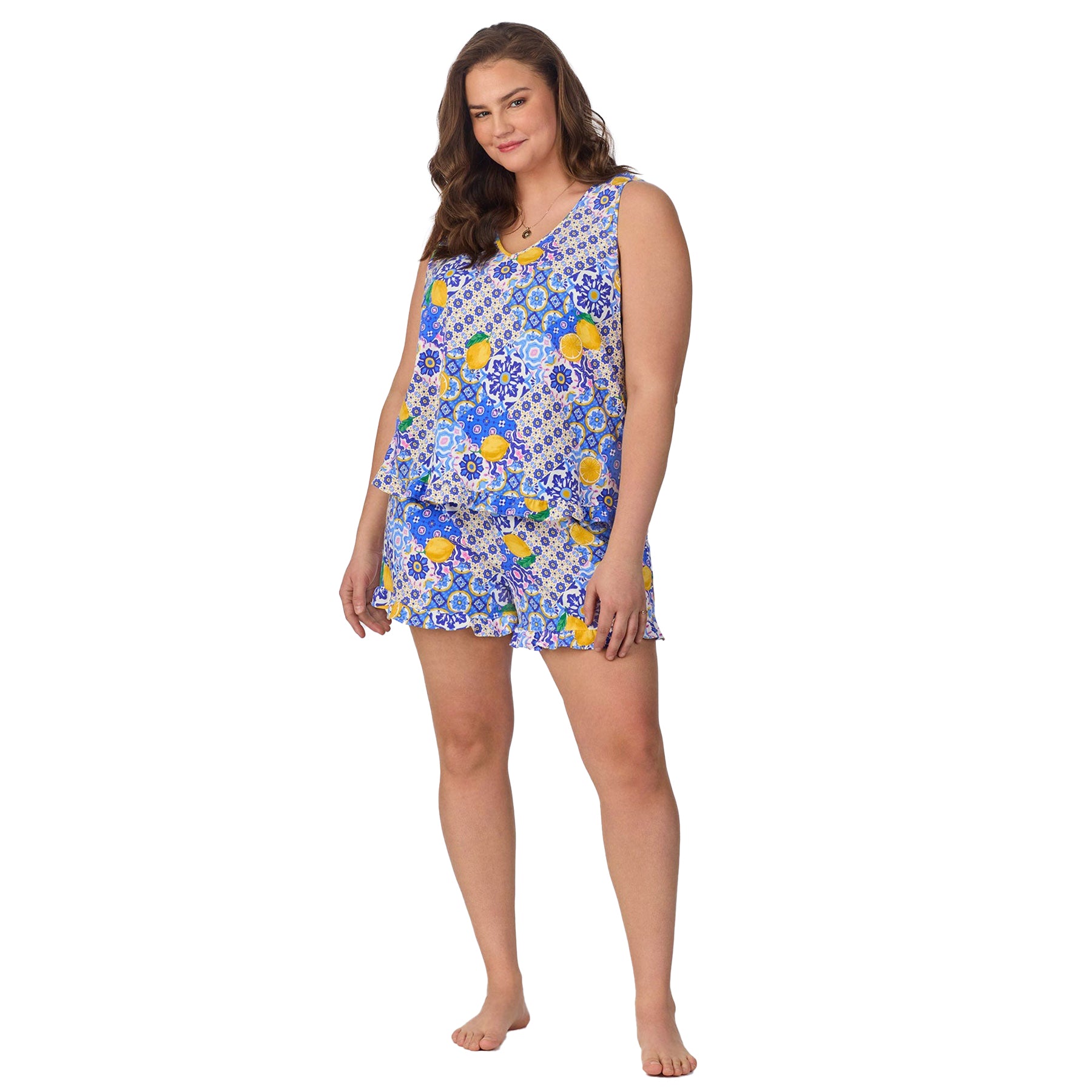 Plus-size model posing from the front in a lemon and tile-printed pajama set with ruffle shorts.