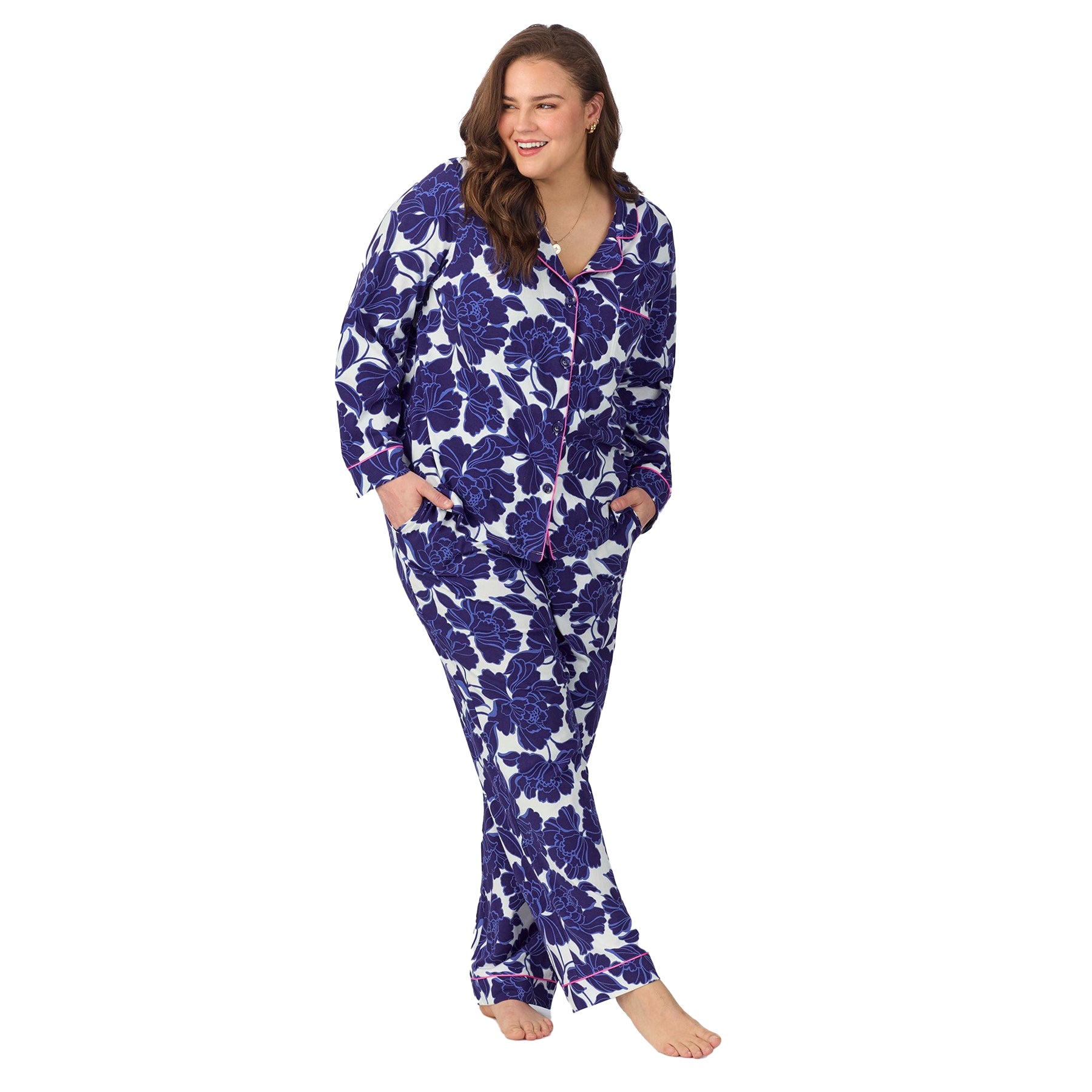 Plus-size model wearing the navy floral pajama set, hands in pockets and smiling.