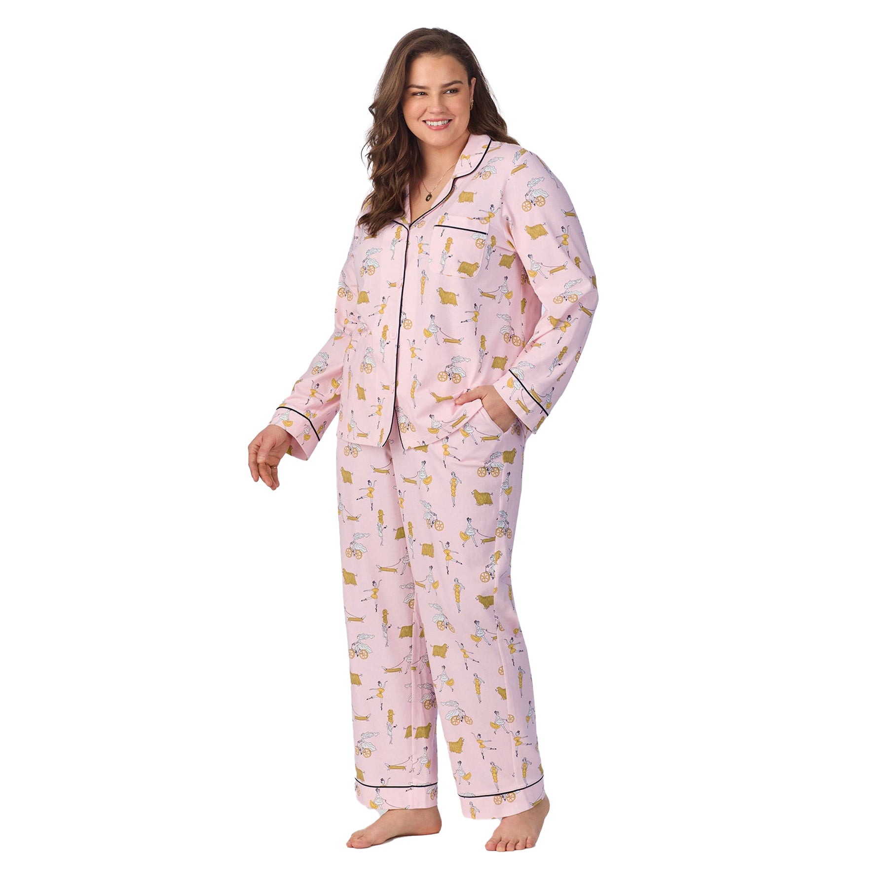 Plus-size model wearing full-length pink pajamas with contrast piping and relaxed fit, facing forward.