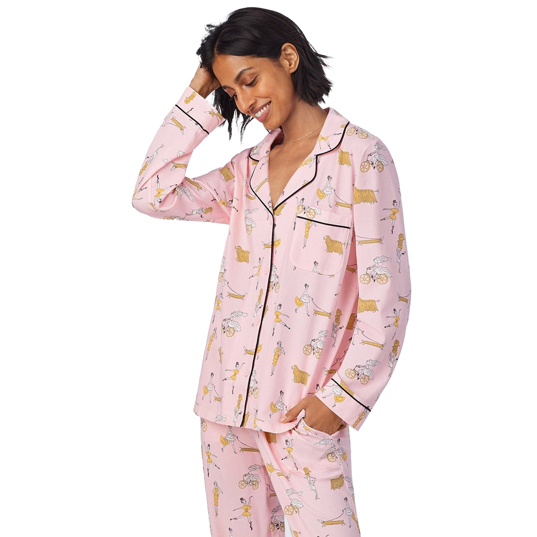 Woman in pink long-sleeve pajama top with a hand in her hair, showing front pocket and contrast trim.