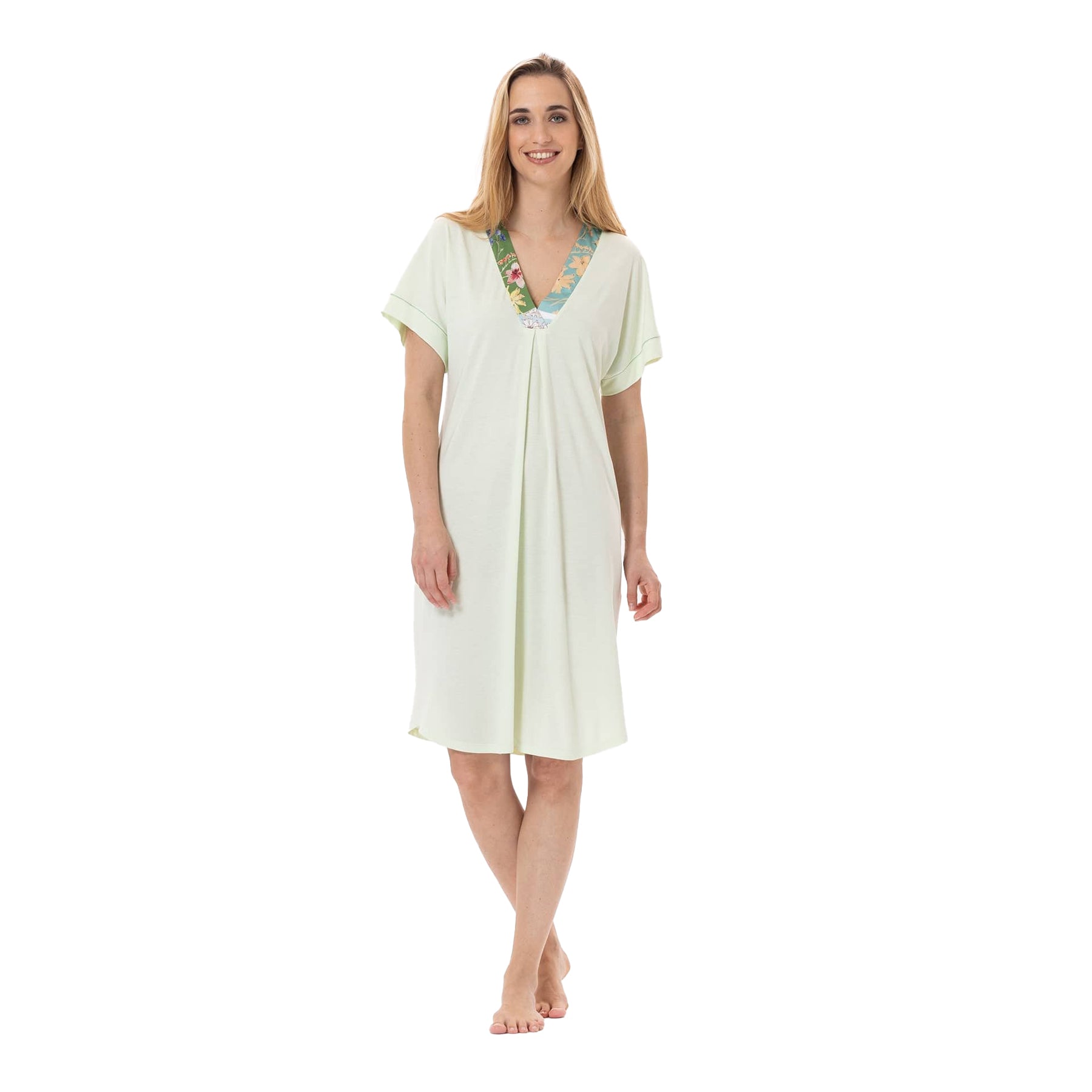 A woman smiling and wearing a light green knee-length nightgown with short sleeves and a floral-trimmed V-neckline.