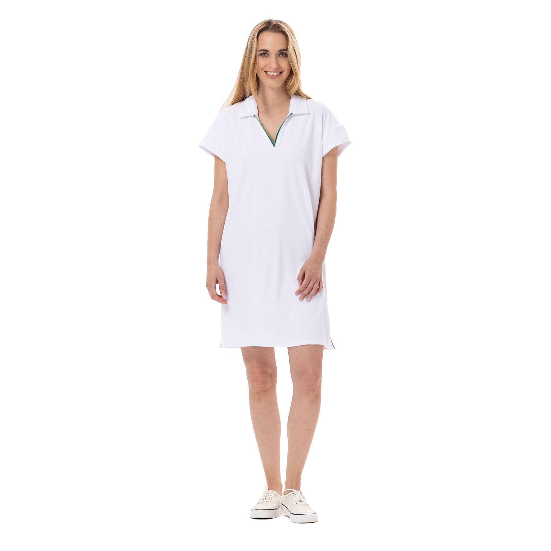 Woman wearing a short-sleeve white terry polo dress with a v-neck collar and green trim, standing and smiling.