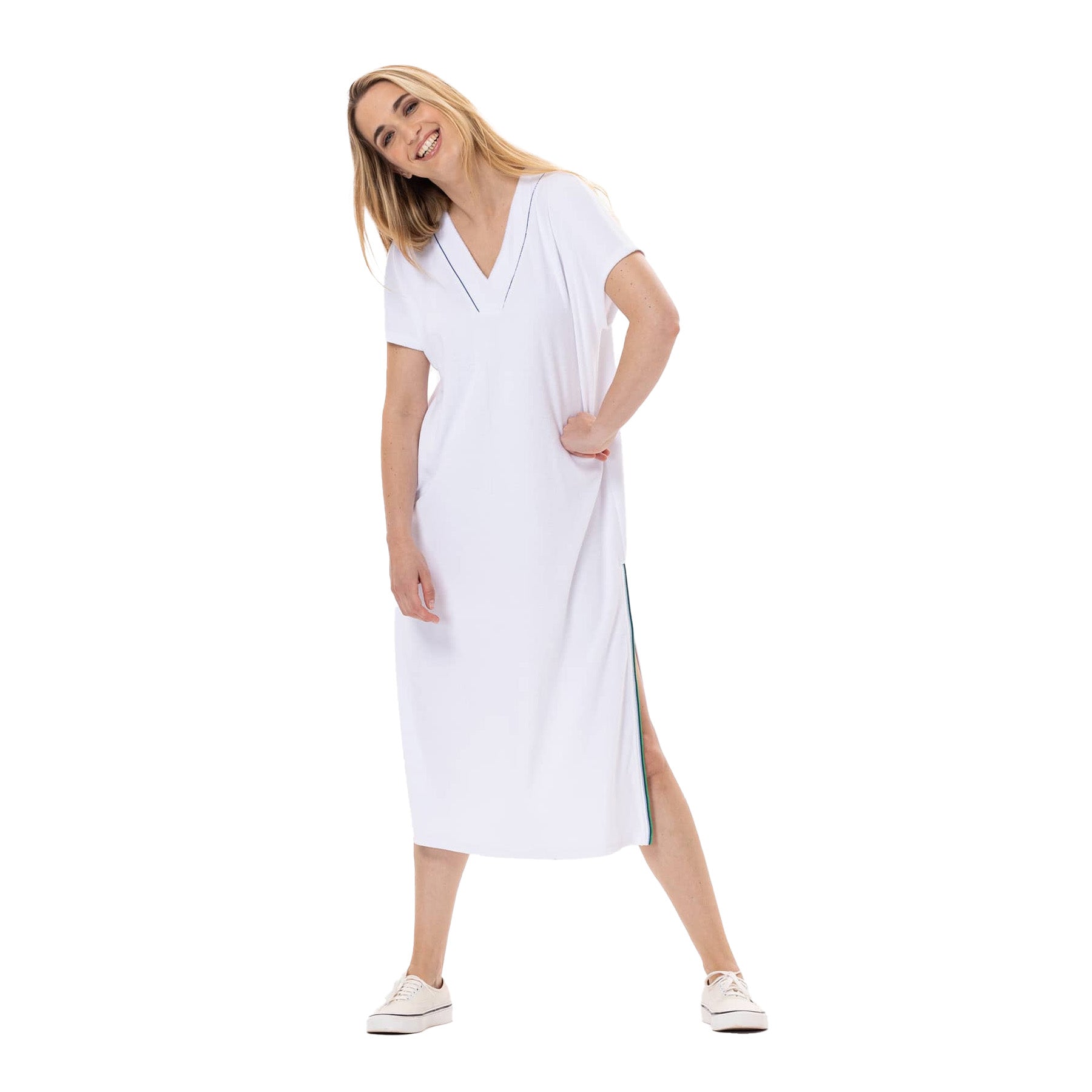 Woman smiling and leaning playfully while wearing a white midi terry dress with side slits and green trim.