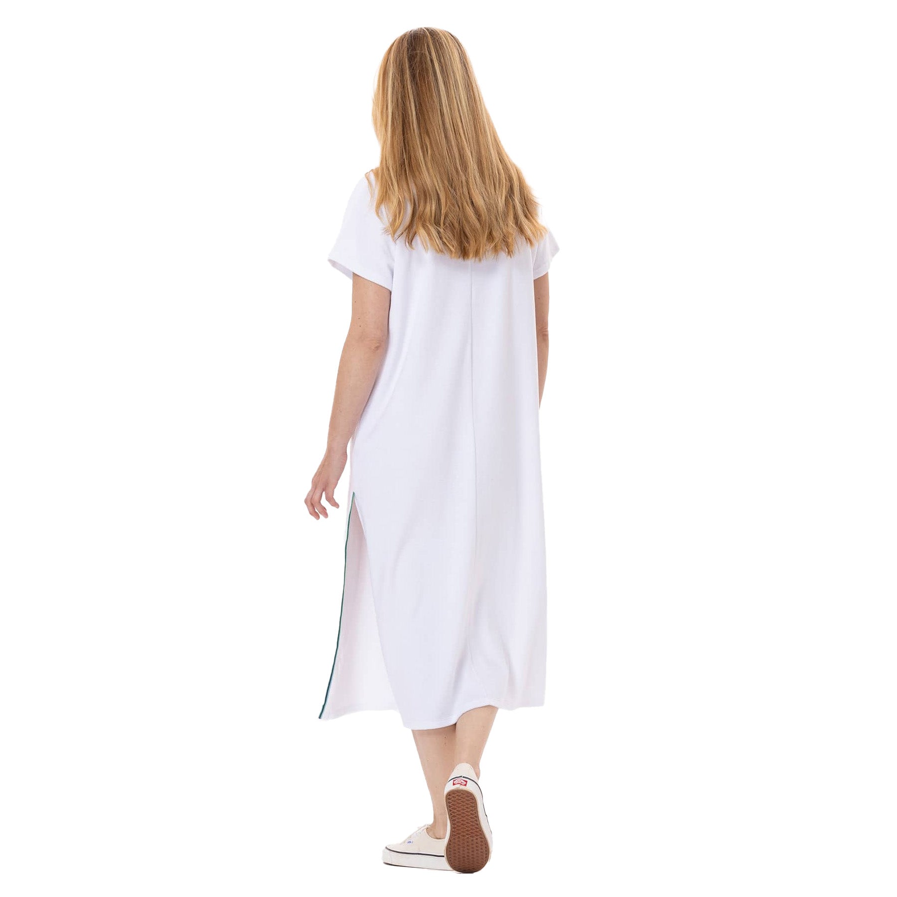 Back view of a woman walking in a white terry midi dress, showing the loose, straight fit and side slit.