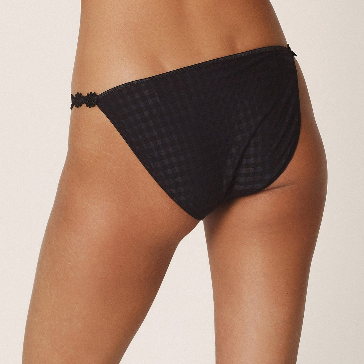Low rise bikini panty in black with embroidered daisy string at hips. Rear view on model.