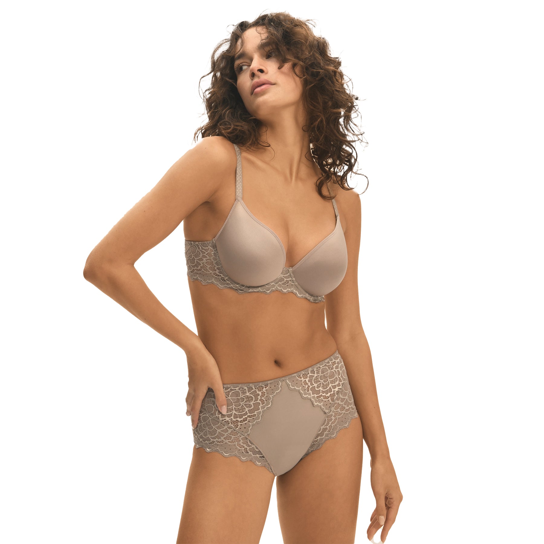 A model showing a grey/nude set of lacey basic lingerie from Simone Perele on a white background, side view.