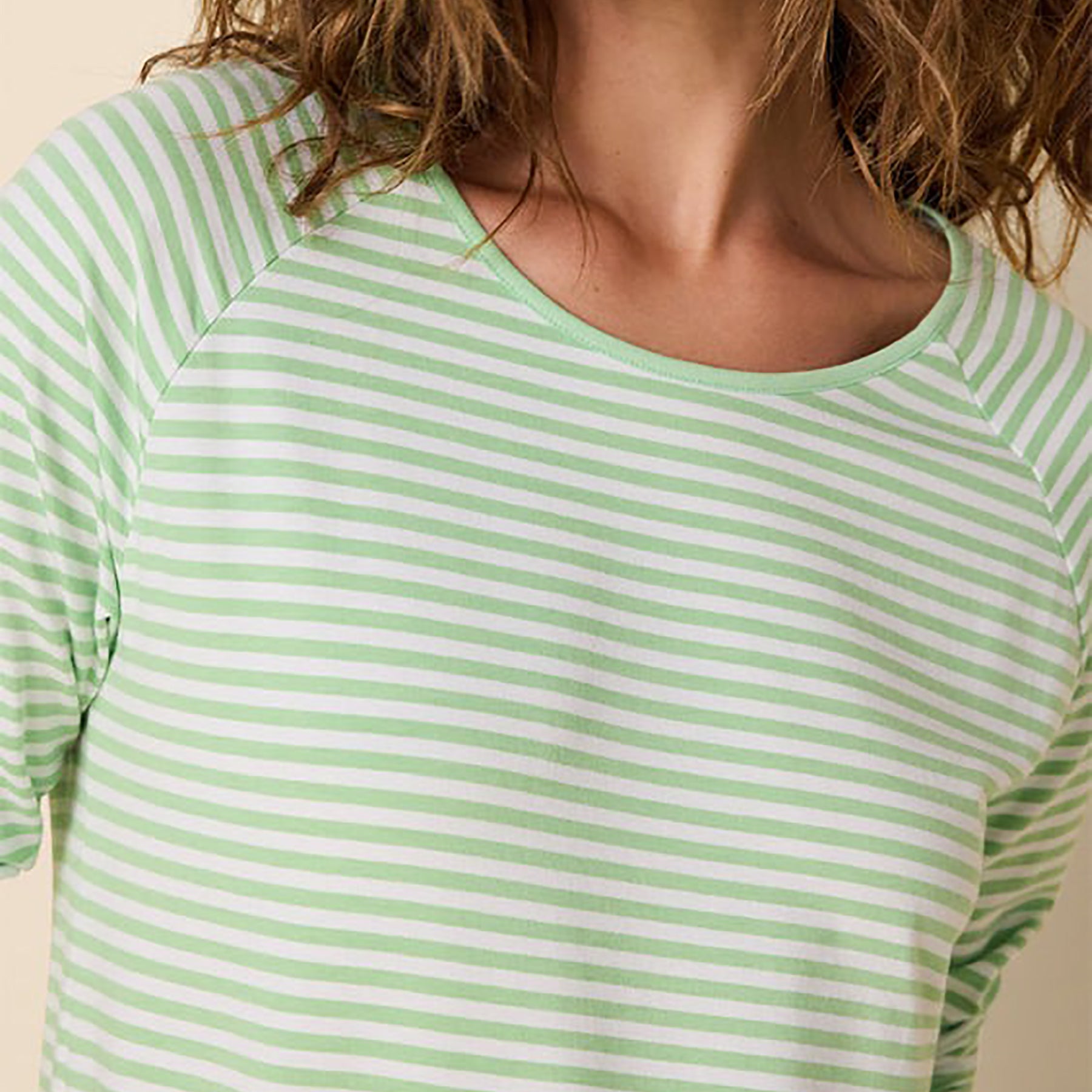 Long sleeve crew neck pj top with matching full length pants in a green stripe on a white background. On model front view closeup of top.