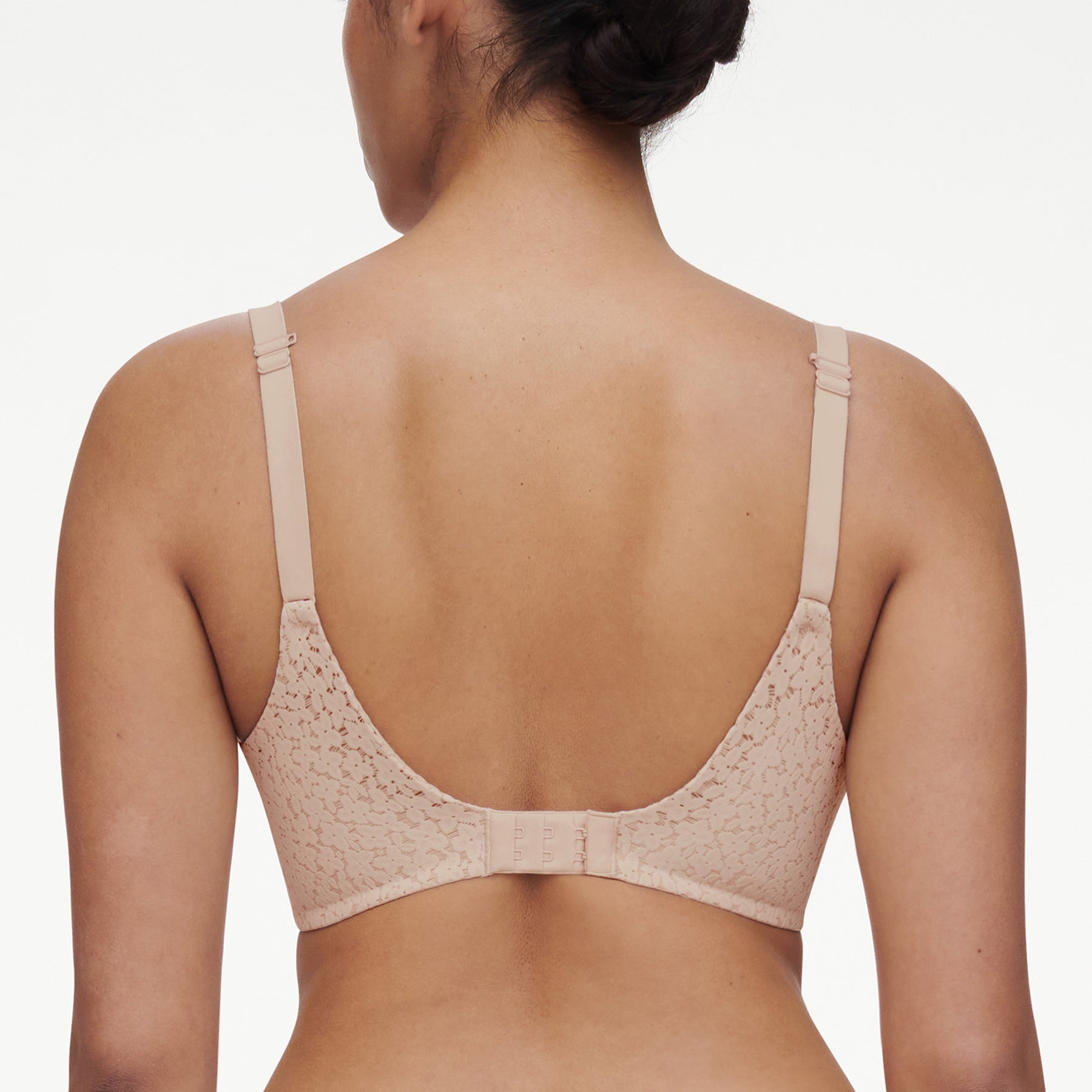 Chantelle molded full cup underwired spacer bra in nude golden beige. Rear view close up on model showing straps worn normally.