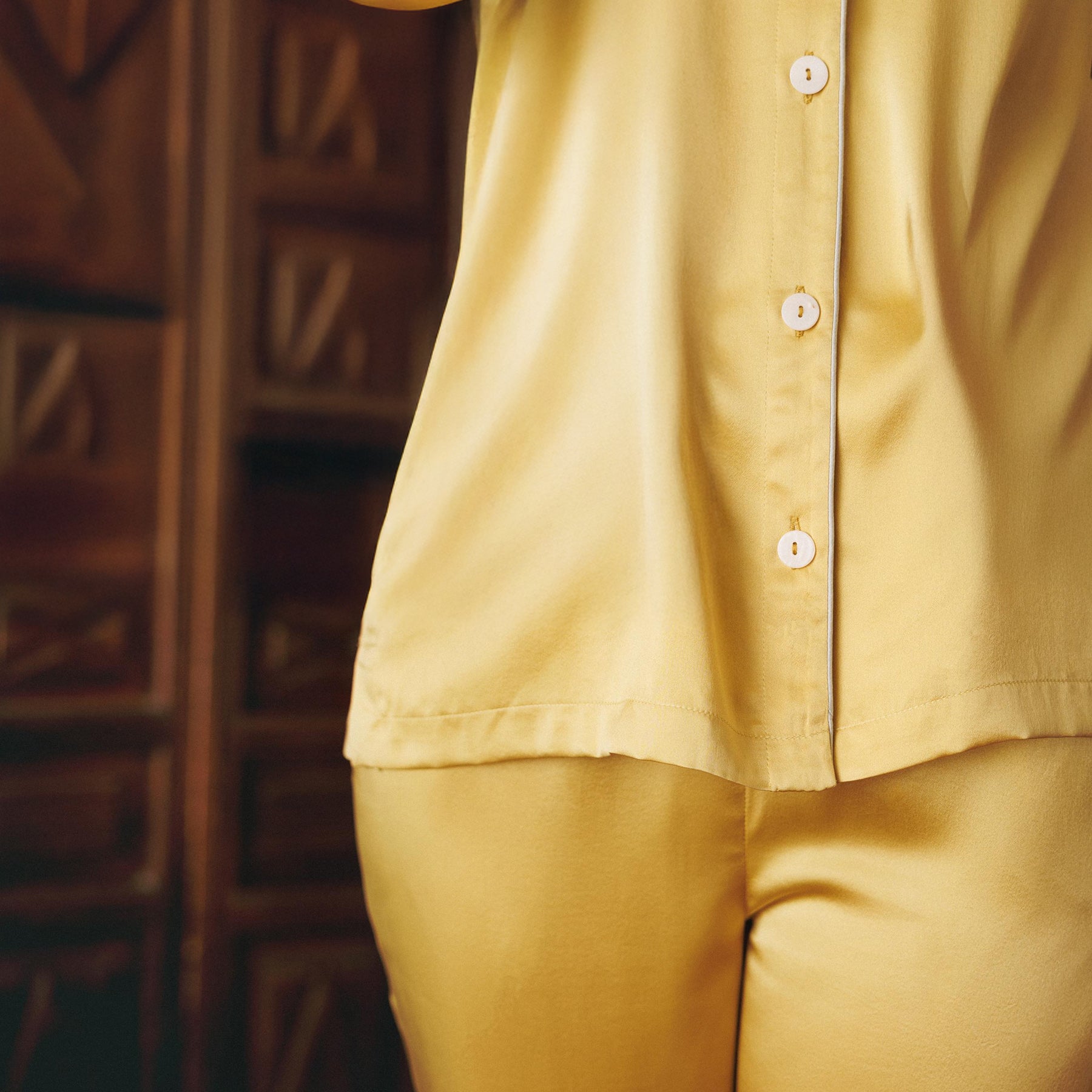 Solid gold classic button up pyjama set made of silk. Closeup on model.