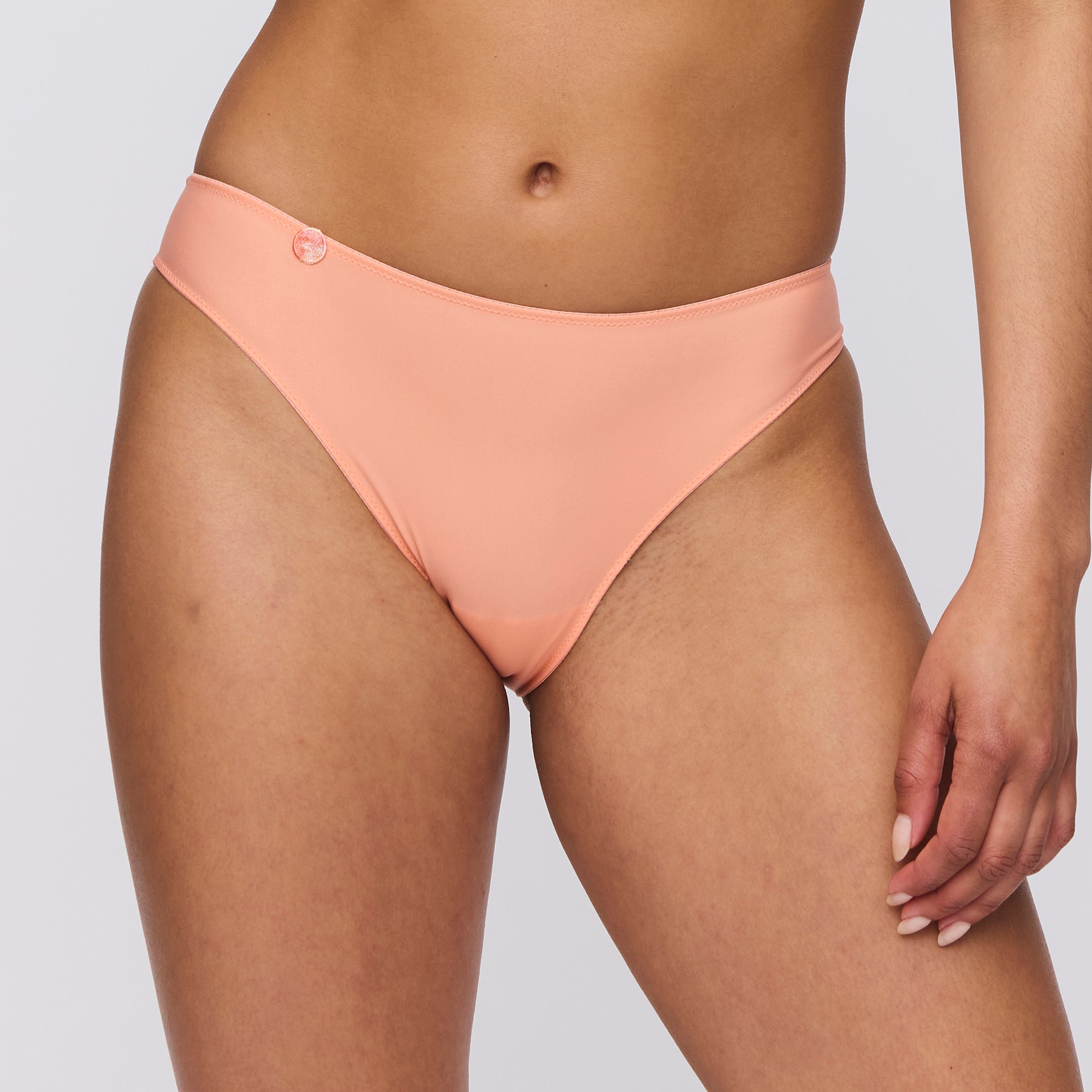 Seamless rio bikini brief in papaya smoothie light orange. Front view close up on model. 