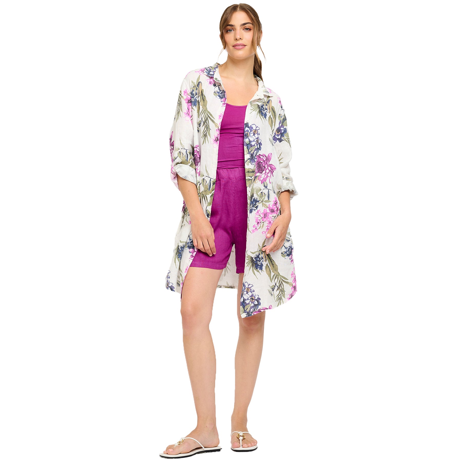 Full view of woman in a white floral button-down shirt dress styled over a fuchsia tank top and shorts - casual chic summer outfit
