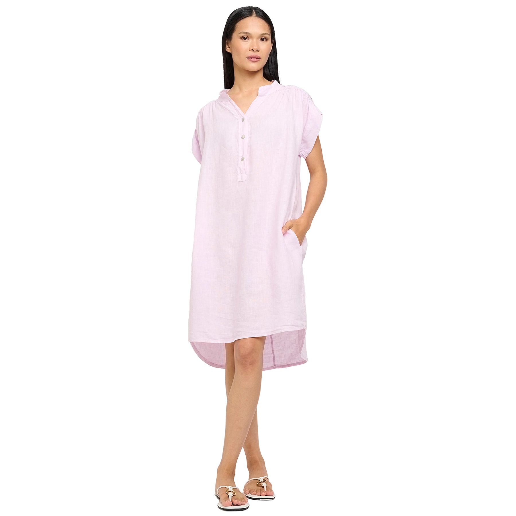 Cap sleeve linen dress in spring lilac with ruched shoulders, henley button up, mock neck, and pockets. Front view on model.