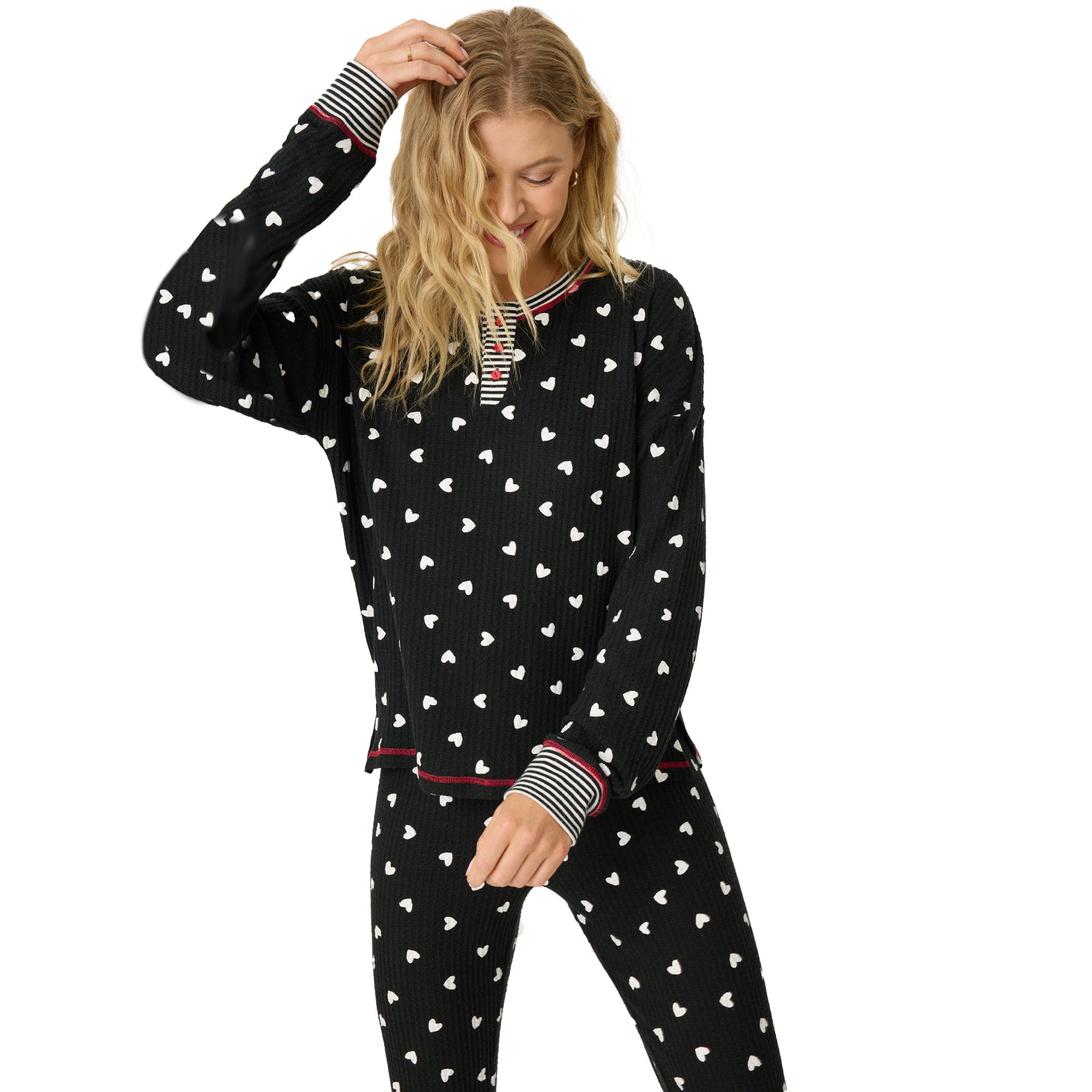 A model posing in a black print with heart pajamas touching her hair.