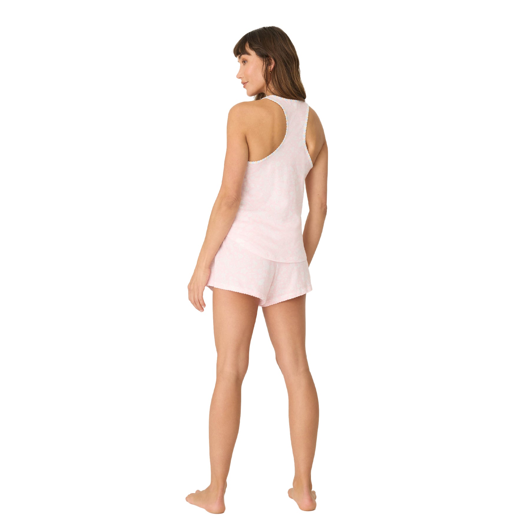 A full rear view of the woman in the pastel pink pajama set, with a racerback tank and matching shorts.