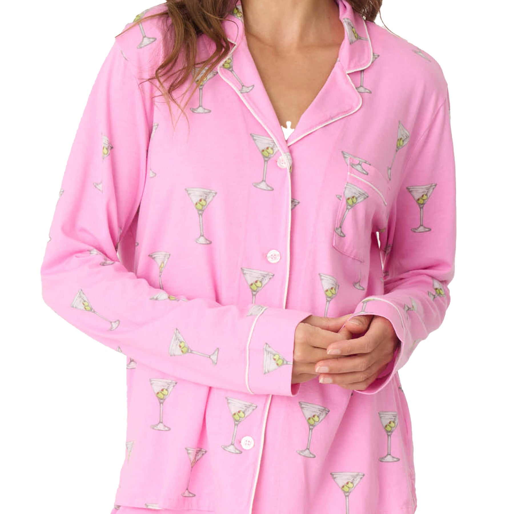 A close-up of a woman’s torso in a pink martini-print pajama top with white buttons and a chest pocket.