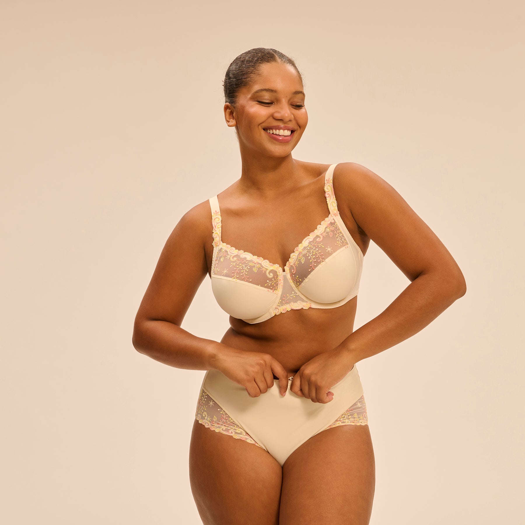 Full brief in pale yellow peach pampa with contrast coral pink embroidery at hips. Front view on model shown with matching 3 part full cup bra.