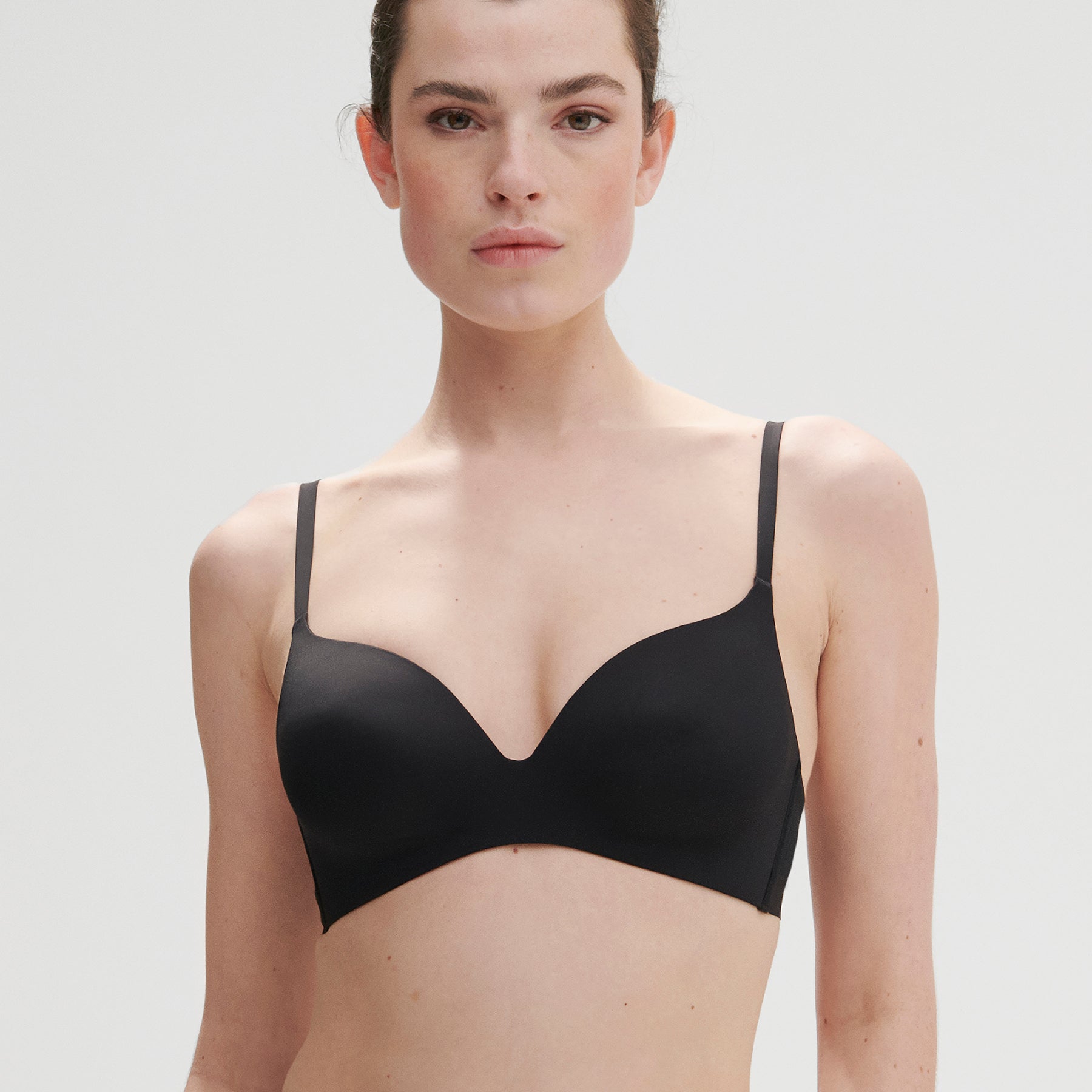 Model wearing black wireless bra front-facing, showing plunge neckline and smooth finish.