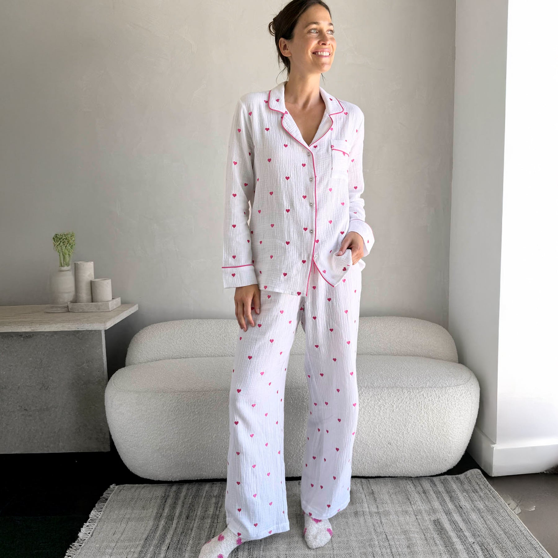 classic button up pyjama set in crinkle cotton in white with mini hot pink embroidered hearts. Matching hot pink contrast piping on trims. Front view on model.