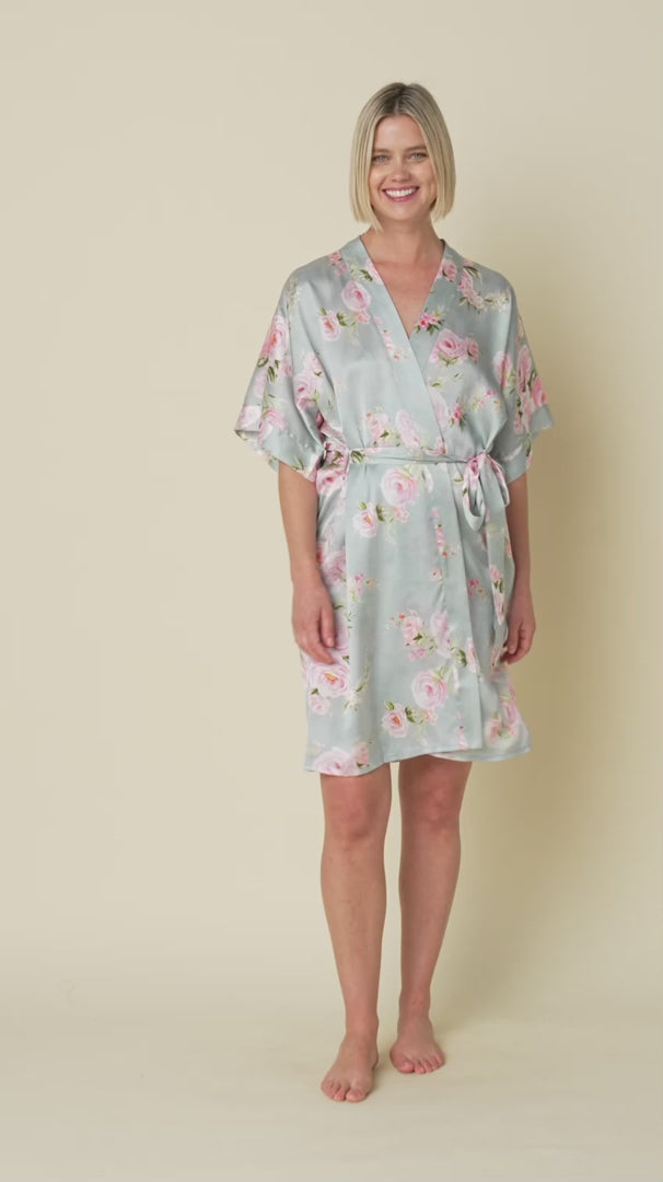 100% silk kimono sleeve short wrap robe in a multicolour floral print on a light blue background. Model shown turning around to show how the robe moves.